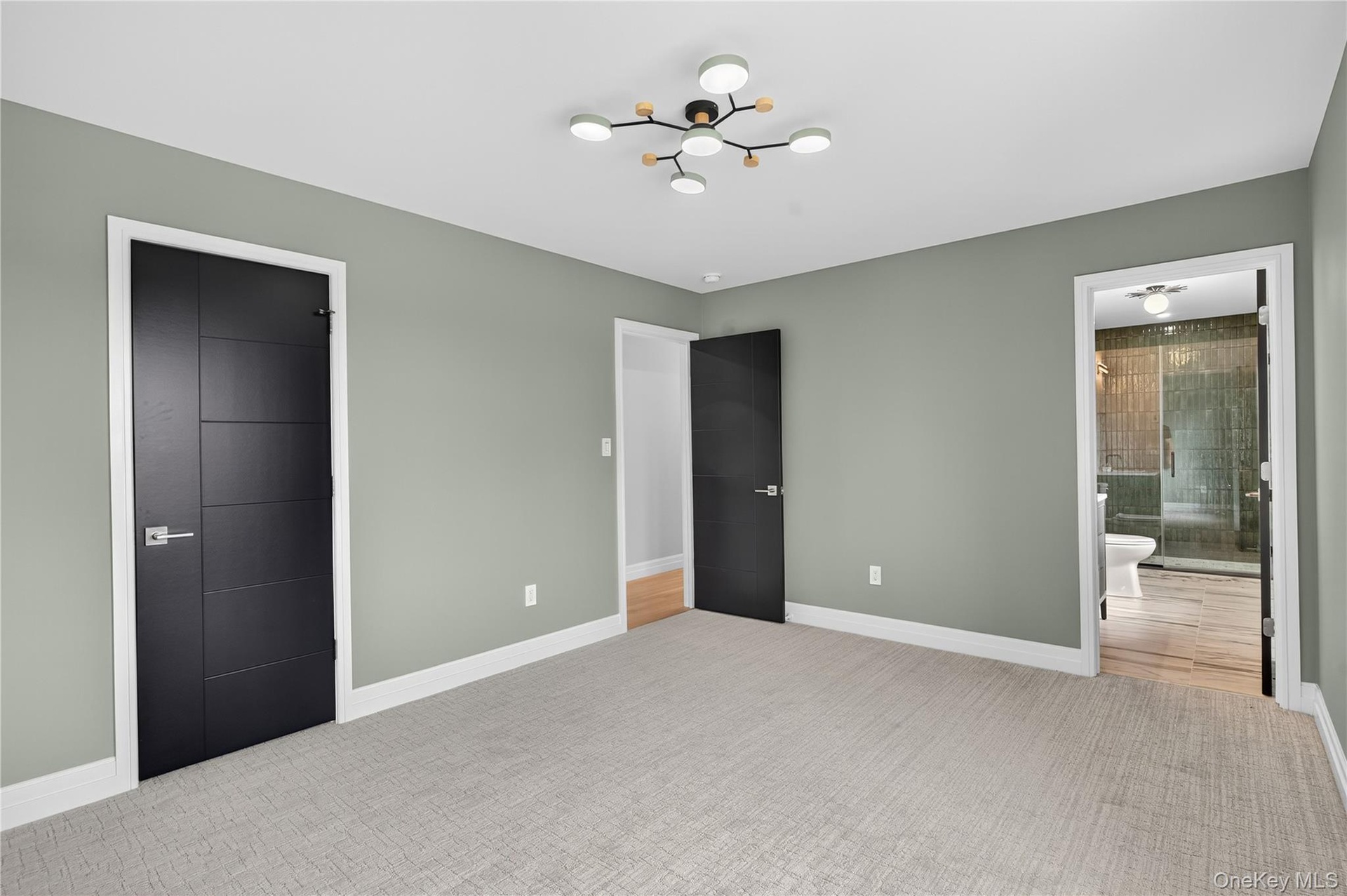 Unfurnished bedroom featuring ensuite bath, carpet flooring, and a chandelier