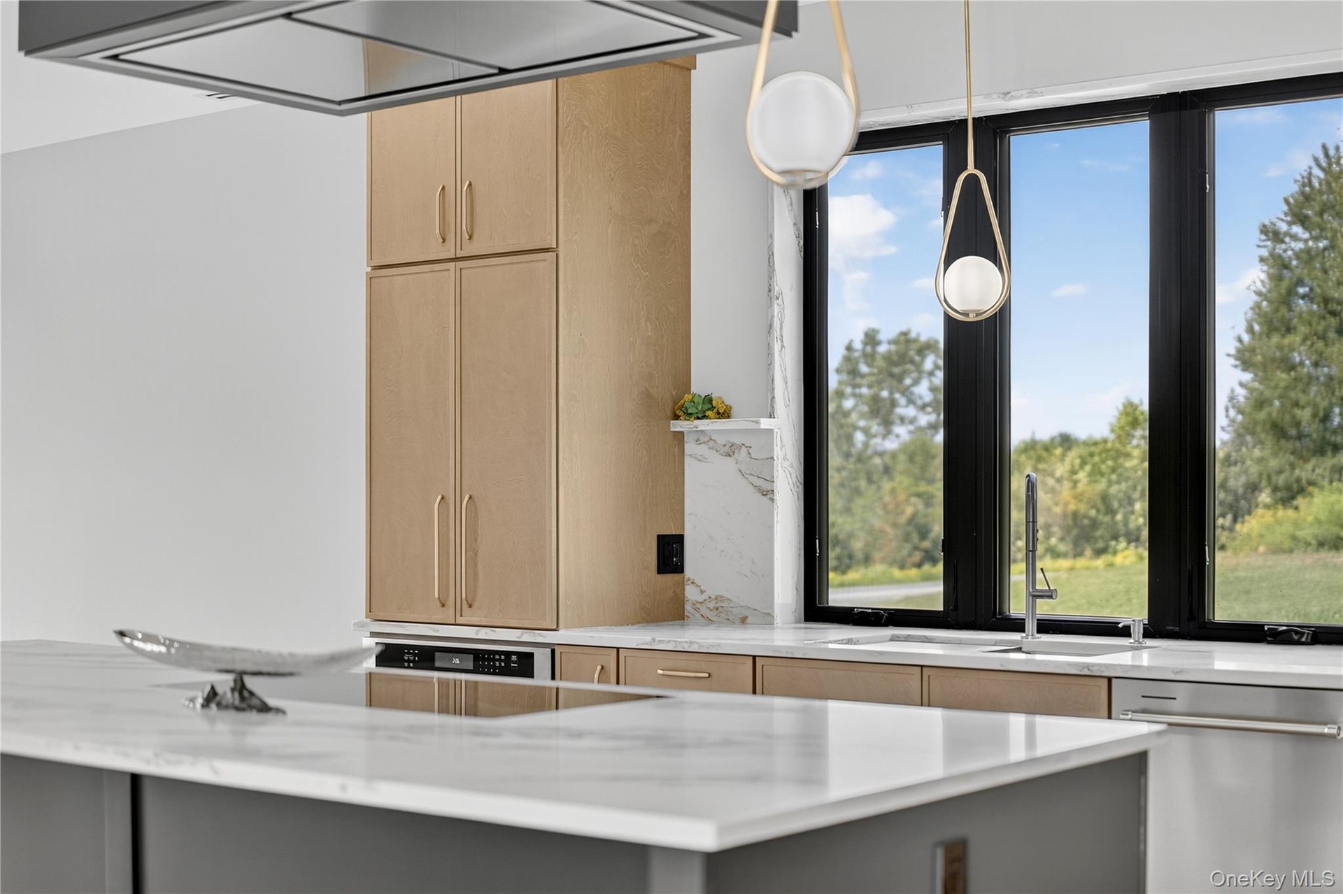 Kitchen with light brown cabinets, stainless steel dishwasher, light stone countertops, and gray cabinets