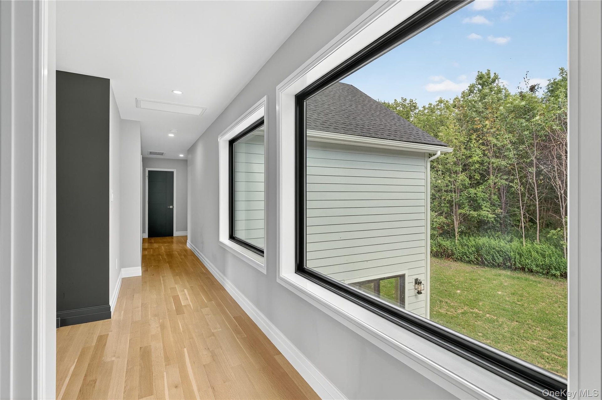 Hall with light wood finished floors and recessed lighting