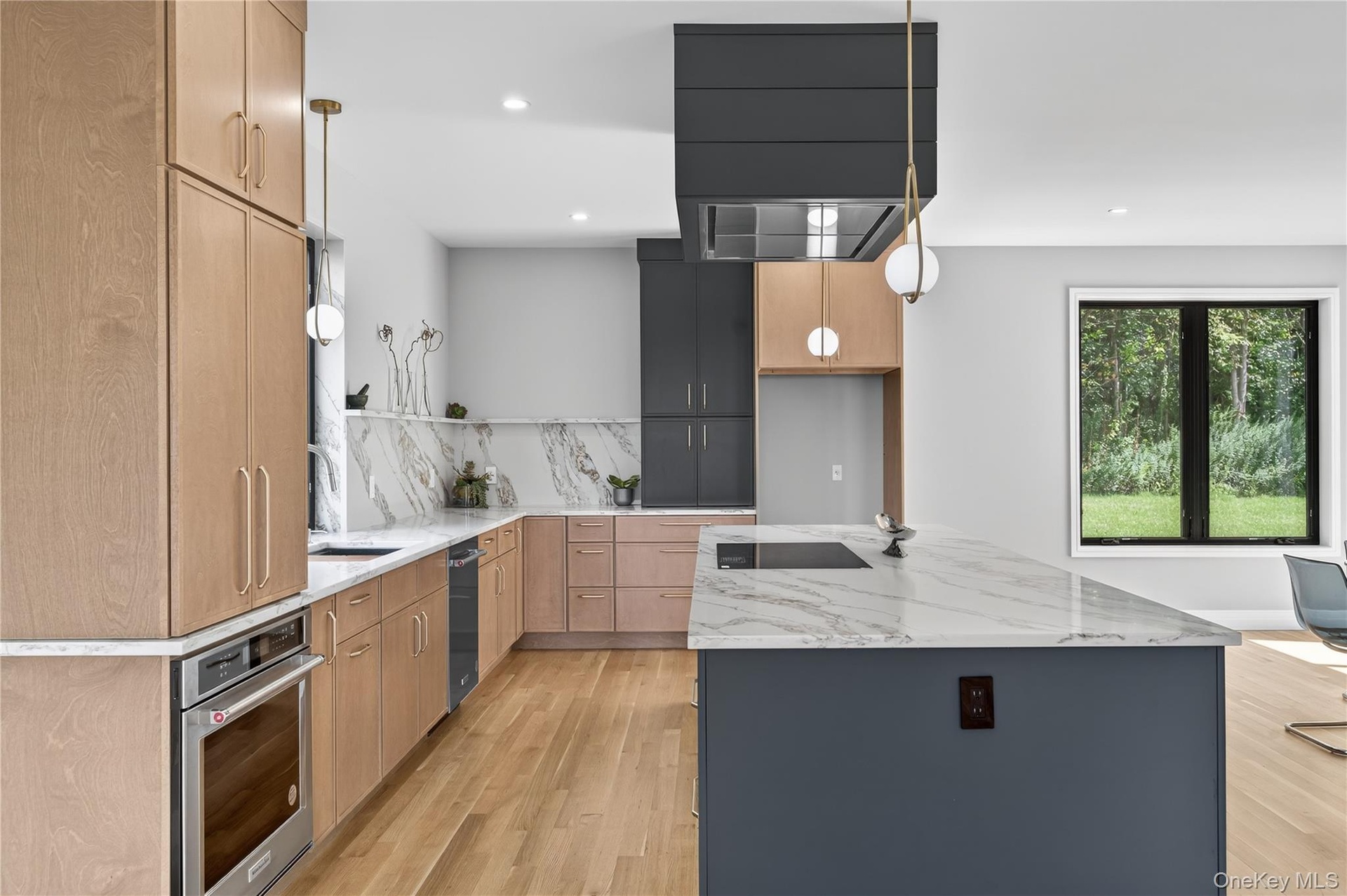 Kitchen featuring light stone countertops, hanging light fixtures, light wood-style flooring, a kitchen island, and oven