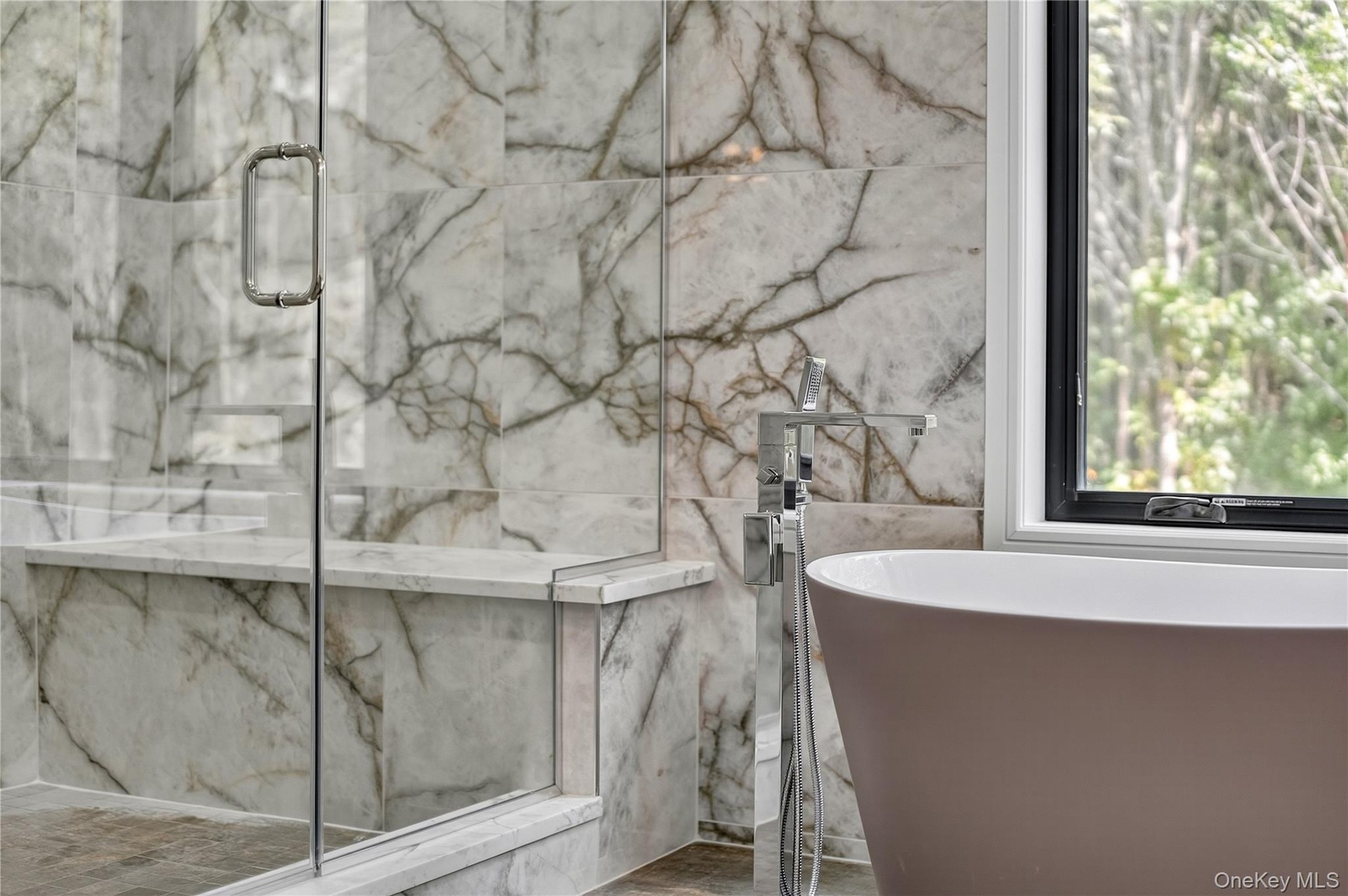 Bathroom with a freestanding bath and a marble finish shower