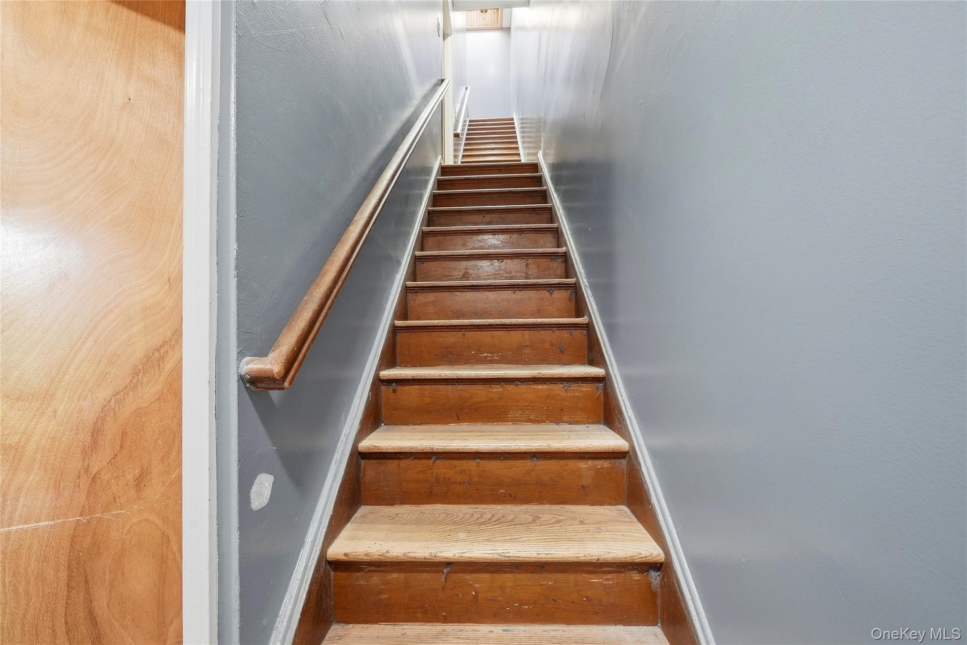 Wooden staircase with a natural wood handrail and light blue painted walls
