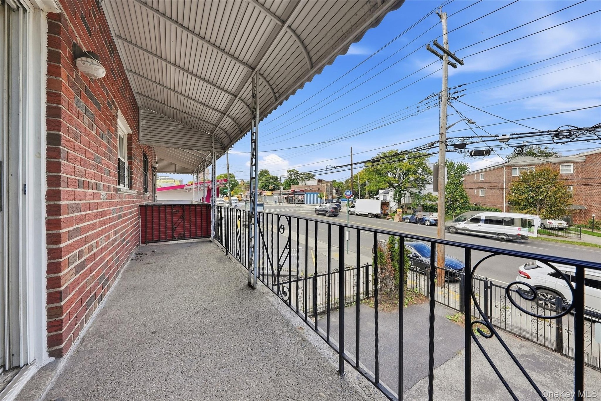 Brick exterior with a covered porch, concrete flooring, and decorative metal railings