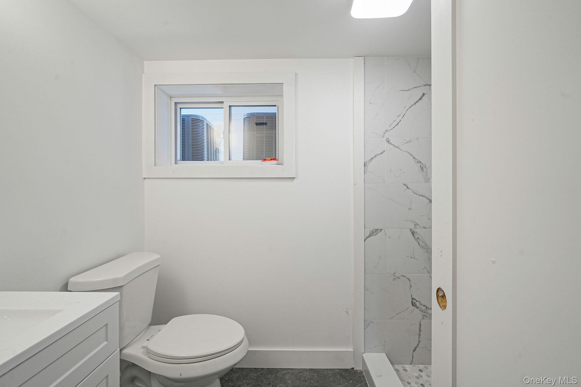 Full bathroom with vanity, a marble finish shower, toilet, and baseboards