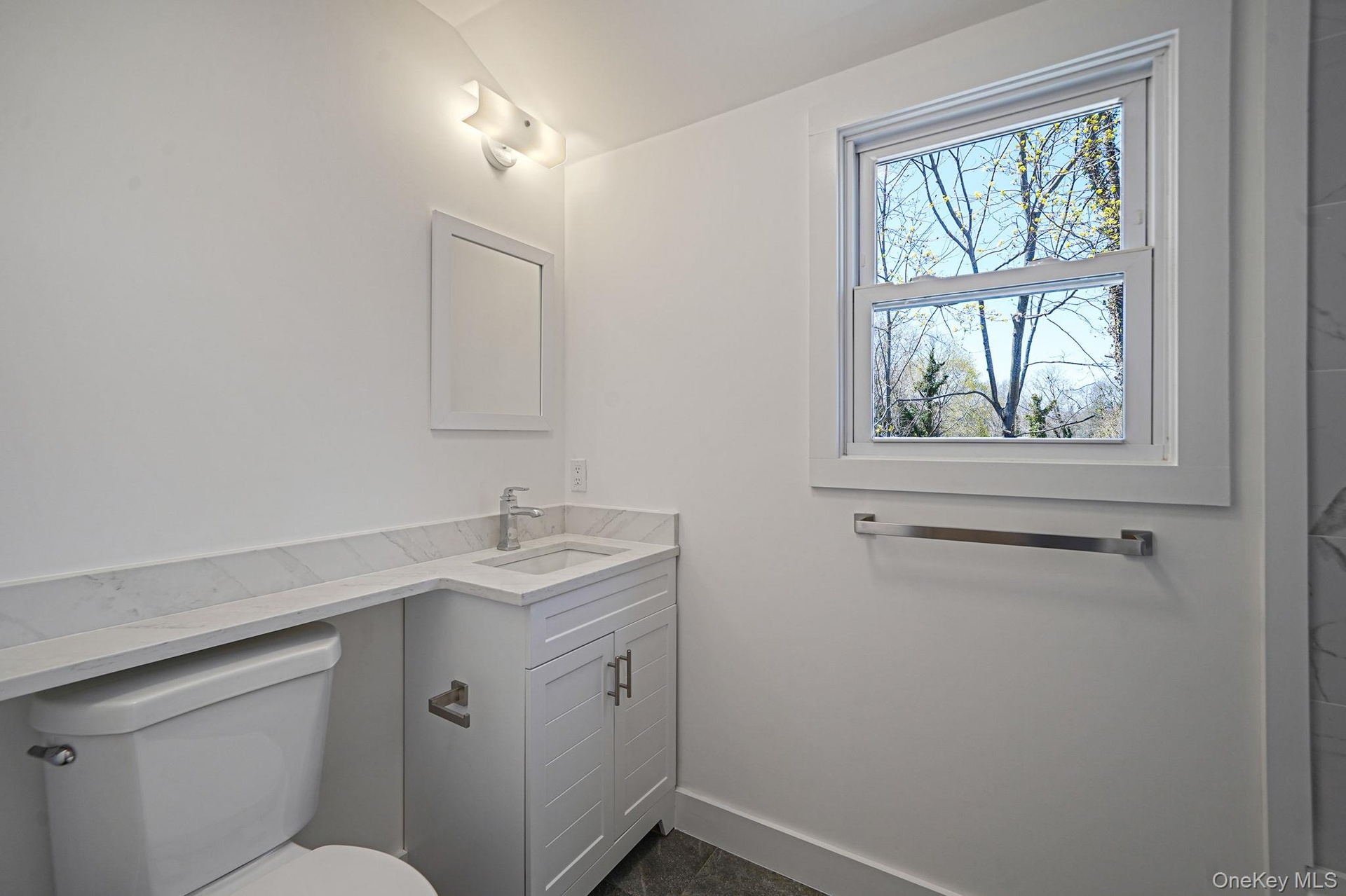 Bathroom with toilet, vanity, and baseboards