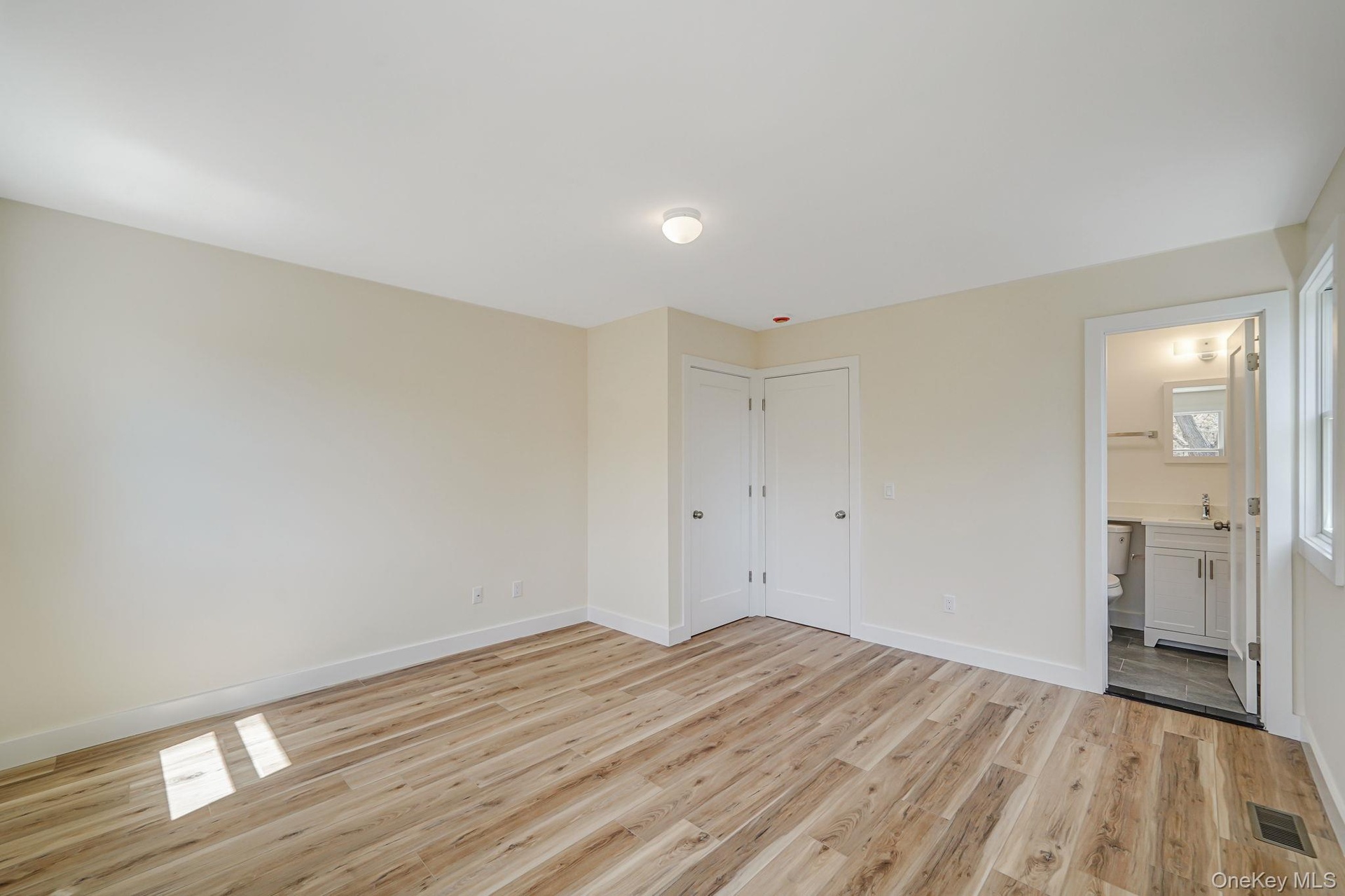 Unfurnished bedroom with light wood-type flooring, baseboards, connected bathroom, and a sink