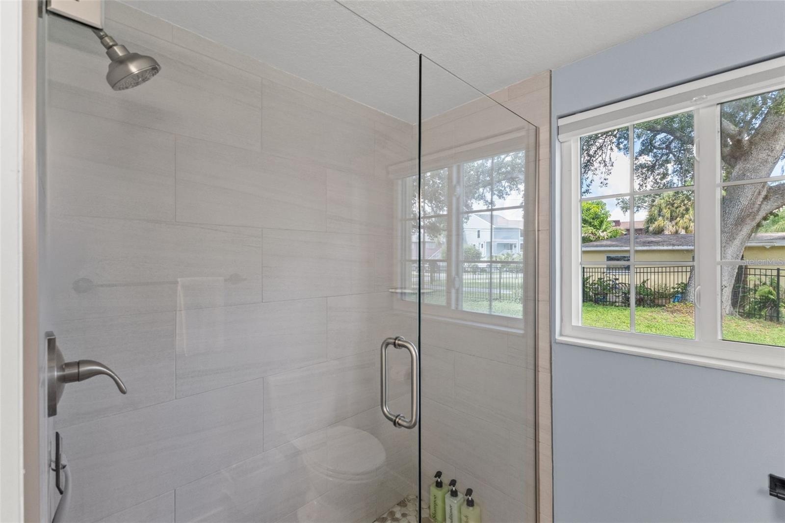 Updated bathroom features a glass-enclosed walk-in shower with large-format tile and pebble-style shower flooring.
