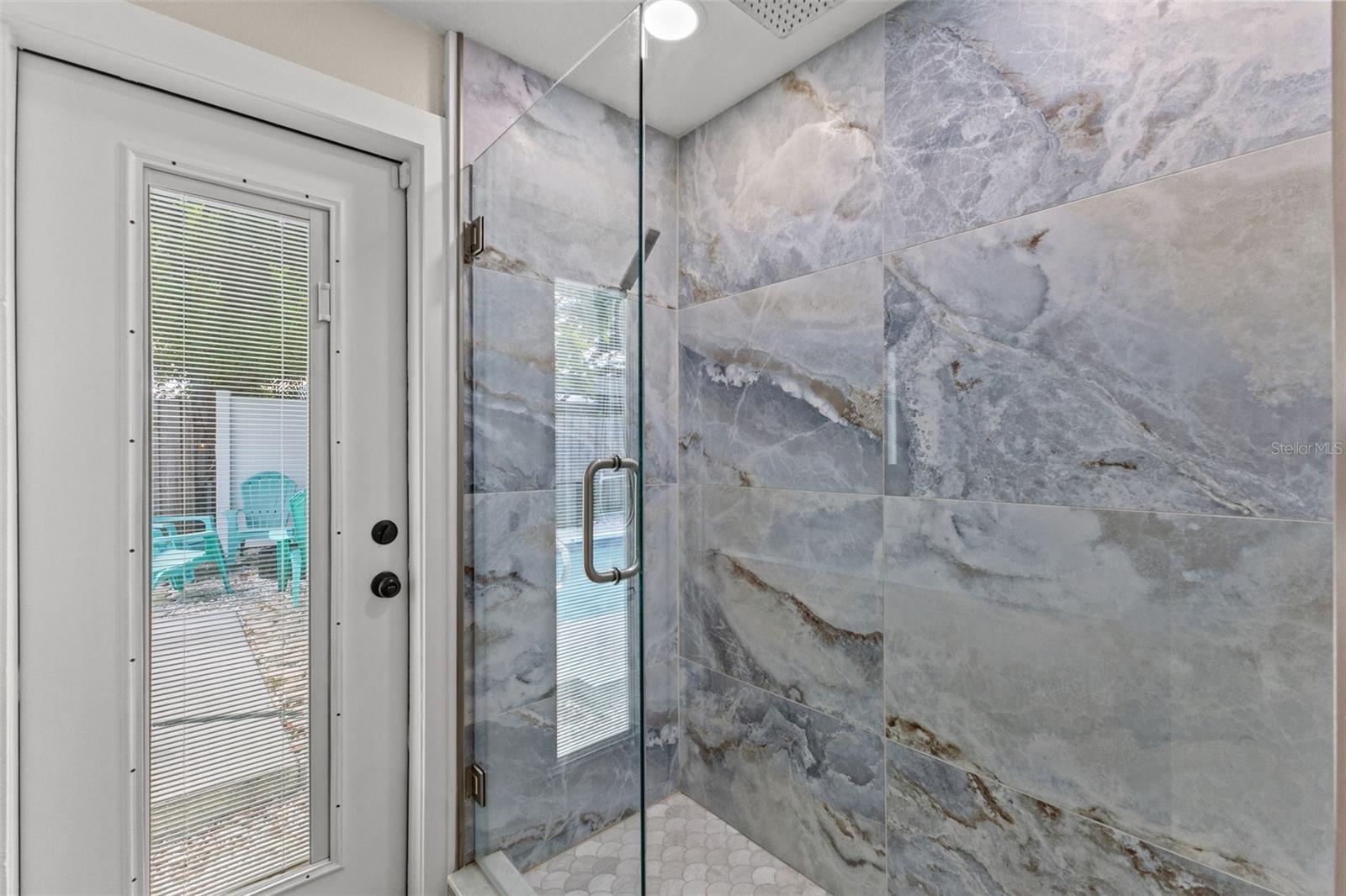 Beautifully tiled walk-in shower with frameless glass enclosure, oversized tile, and a rainfall-style showerhead.