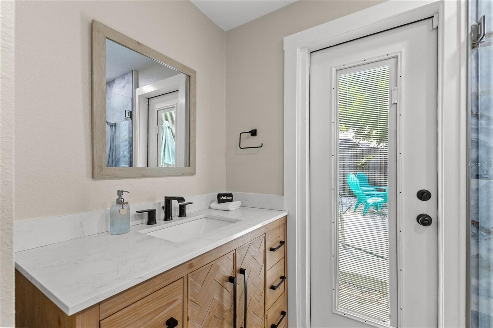 Updated vanity with modern black fixtures and direct exterior access—especially convenient when enjoying the pool.