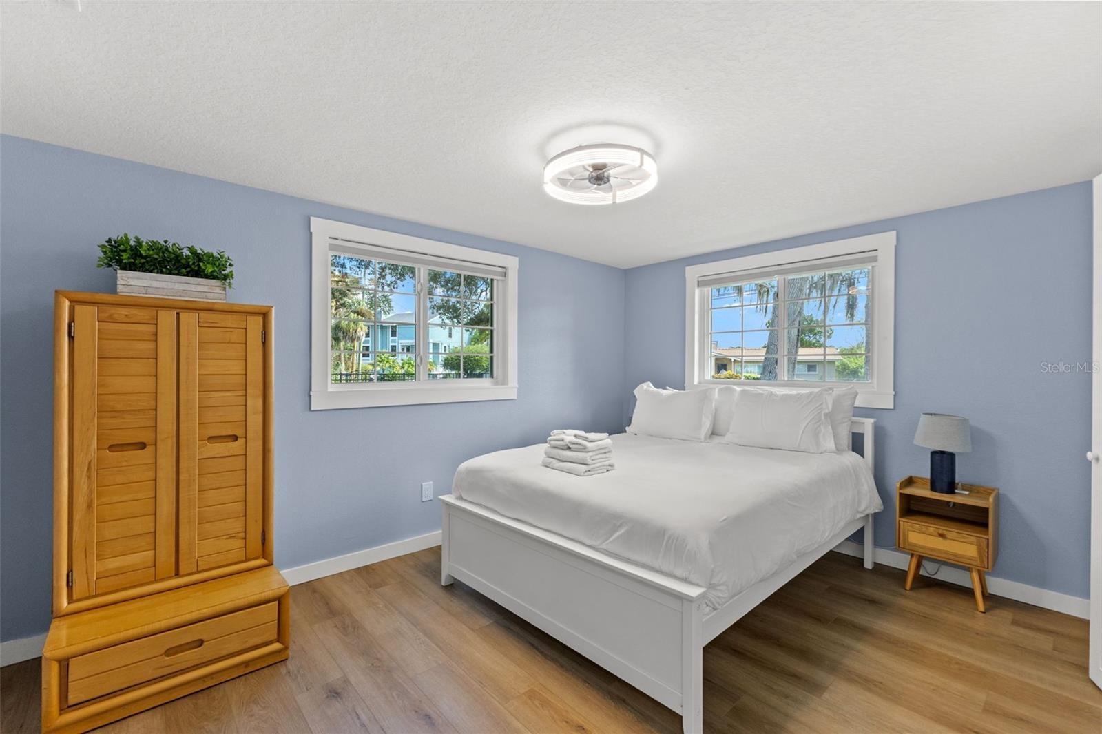 Bright bedroom with luxury vinyl plank flooring, two windows, and updated trim.