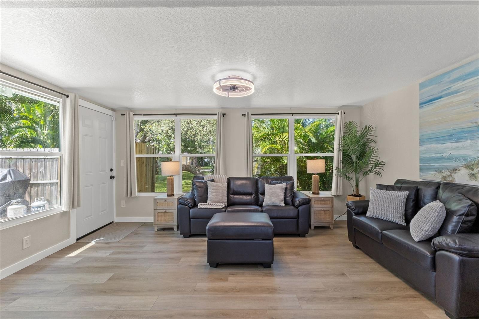 A wall of windows fills the room with natural light while overlooking the surrounding tropical landscaping.