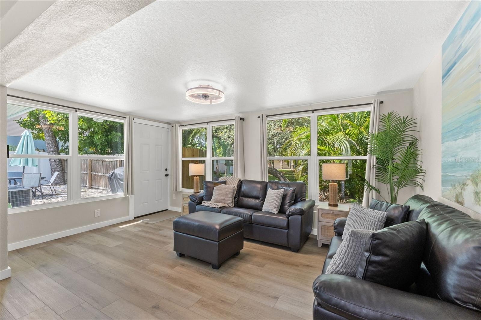 Multiple windows and direct outdoor access connect this bright living space to the home’s outdoor areas.