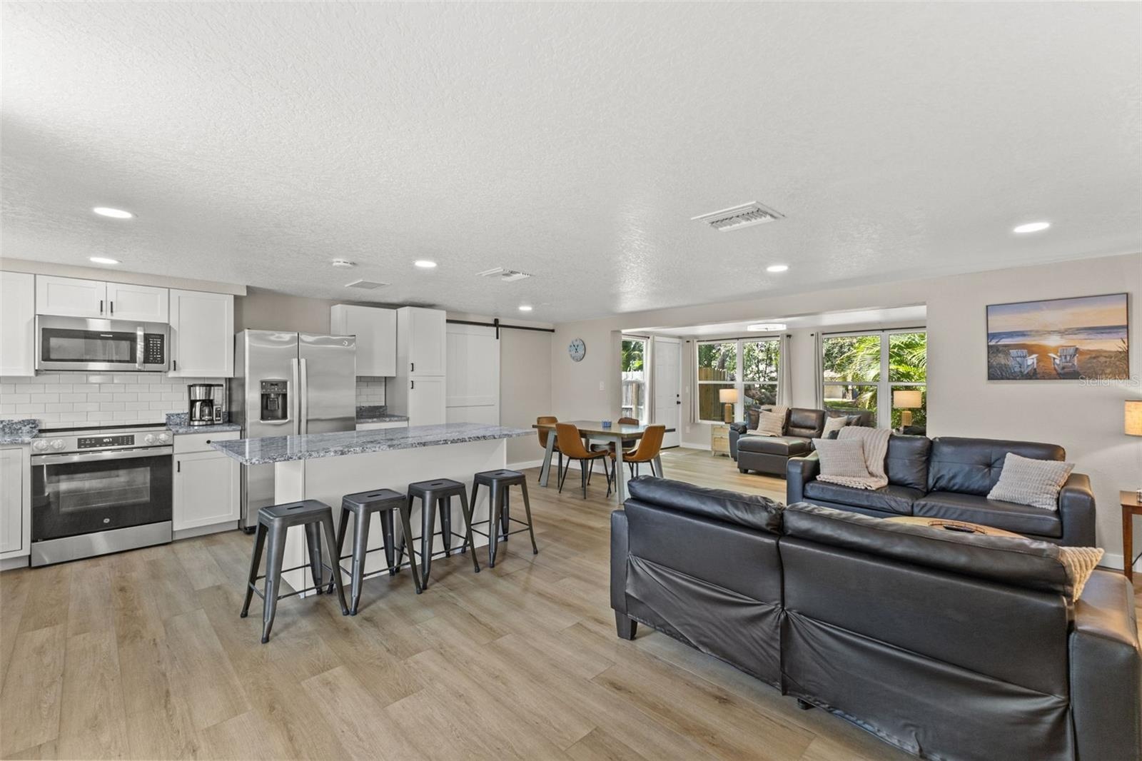 The renovated kitchen opens to the main living areas and features new cabinetry, granite countertops, stainless steel appliances, and a large gatherin