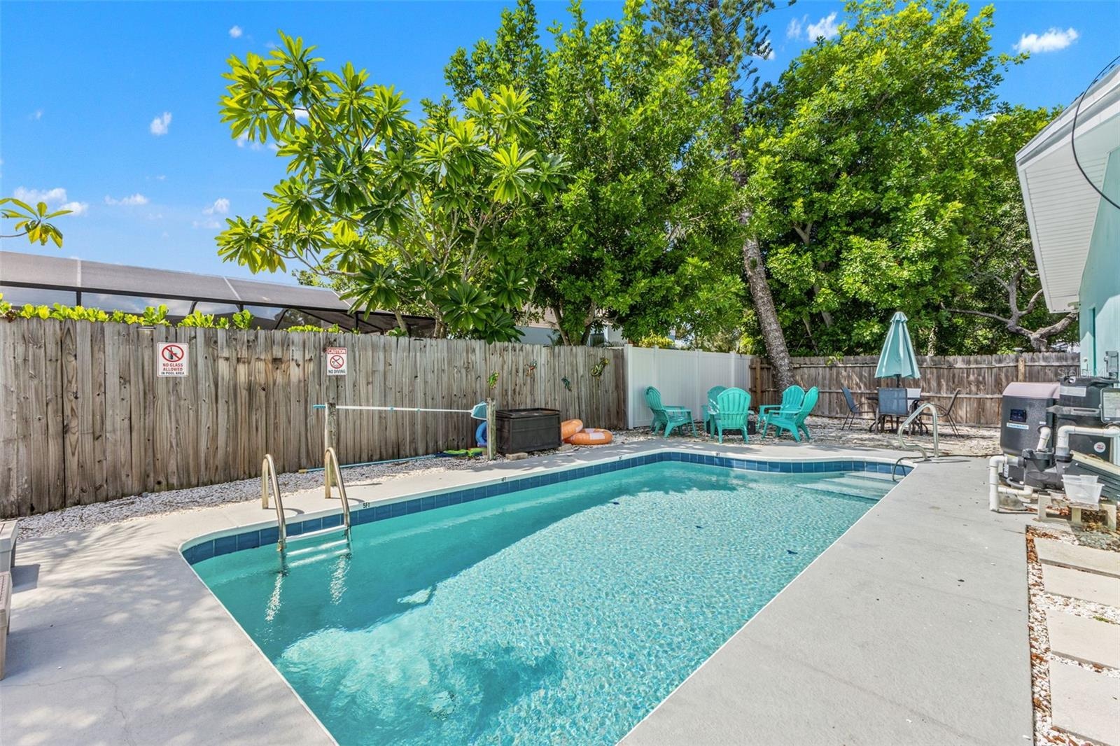 Private heated pool surrounded by mature landscaping and multiple spaces for lounging and relaxing outdoors.