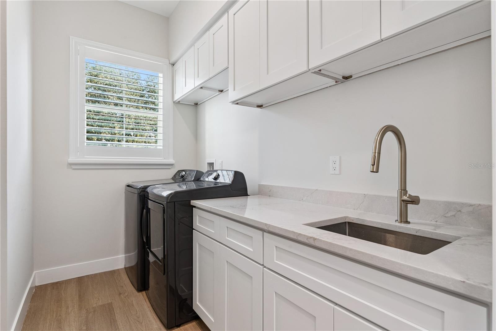 The laundry room includes a washer, dryer, utility sink, and upper and lower cabinetry.
