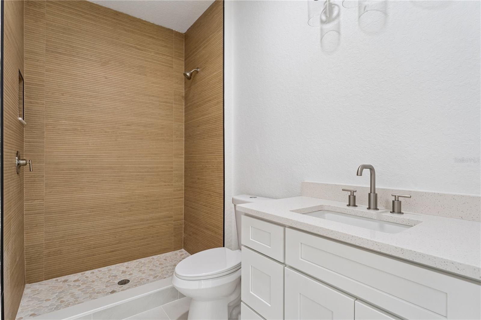 This bathroom features a white vanity and a walk-in shower with wood-look wall tile.