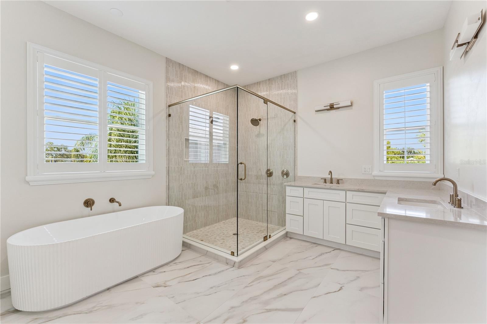 A freestanding tub, glass-enclosed shower, and two sinks define this spacious bathroom.