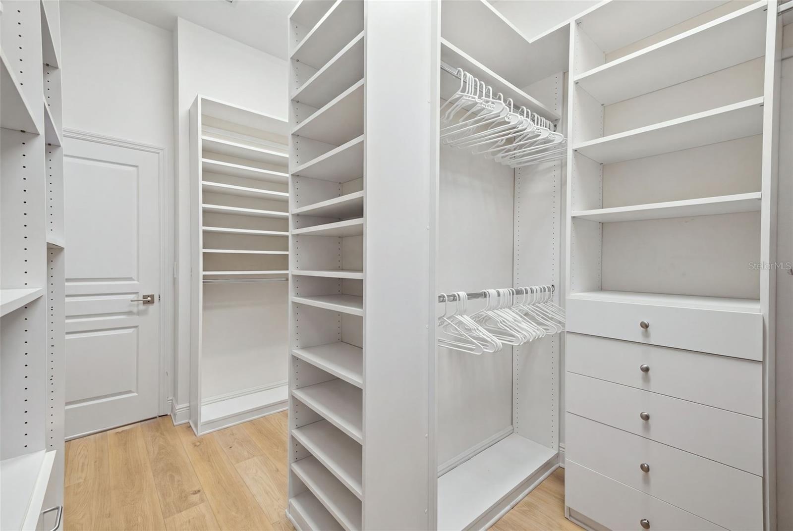 Primary walk in closet with custom shelving