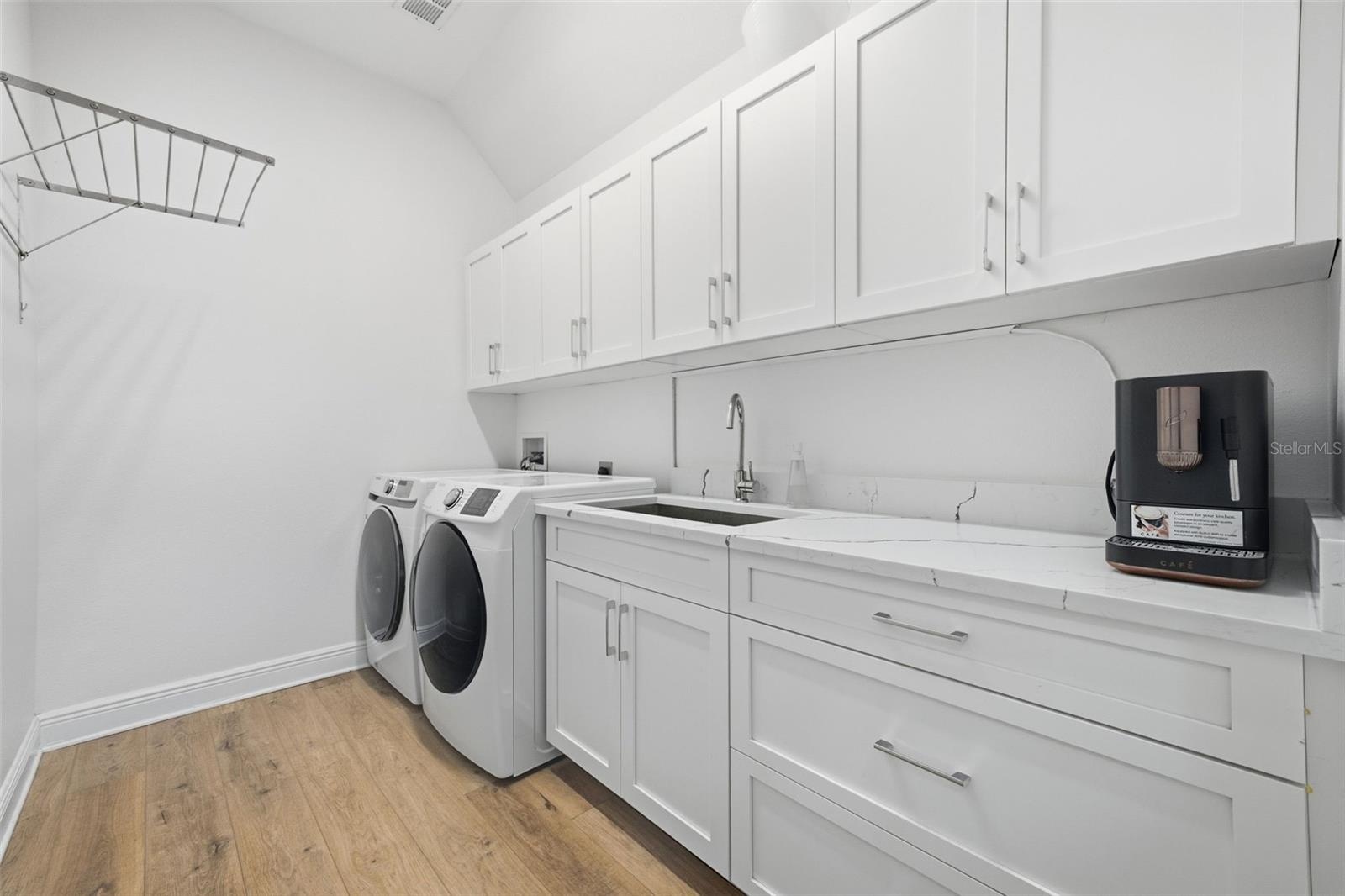 First floor laundry room with counter space, cabinets for storage and a utility sink