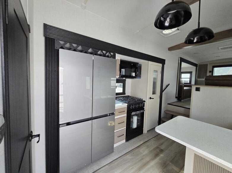 RV: Full-size double-door fridge freezer, full-size gas stove top and oven with microwave above.