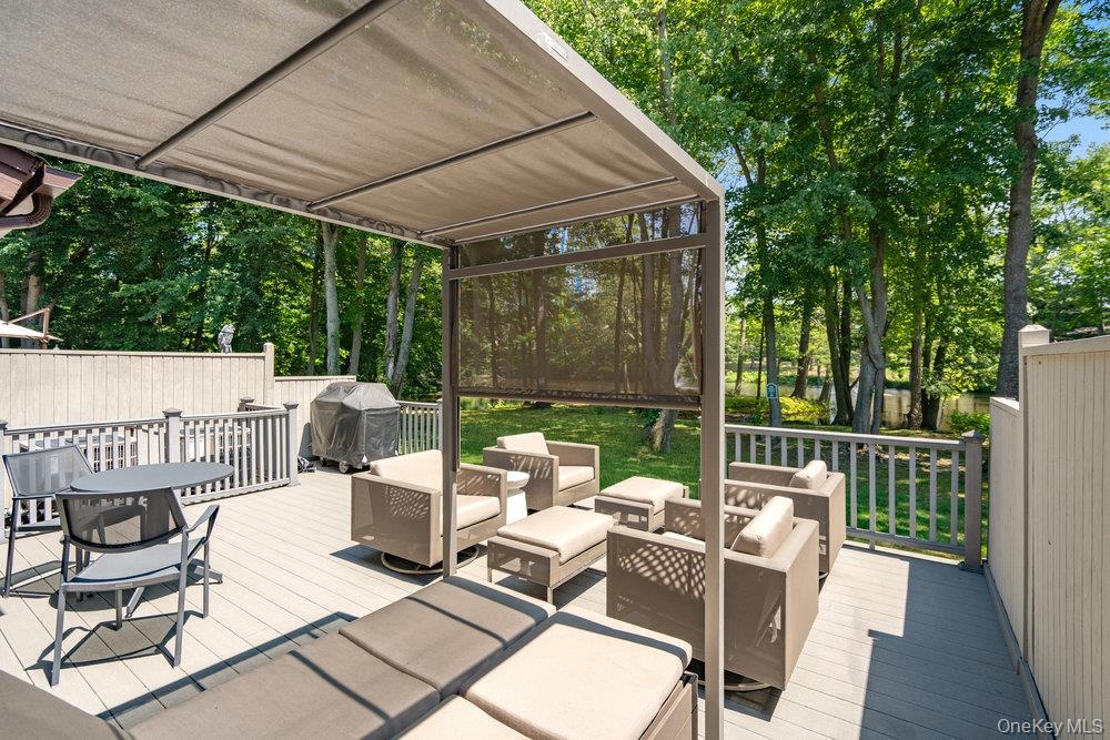 Expansive outdoor deck featuring a fixed pergola, privacy screening, and wood-finish decking