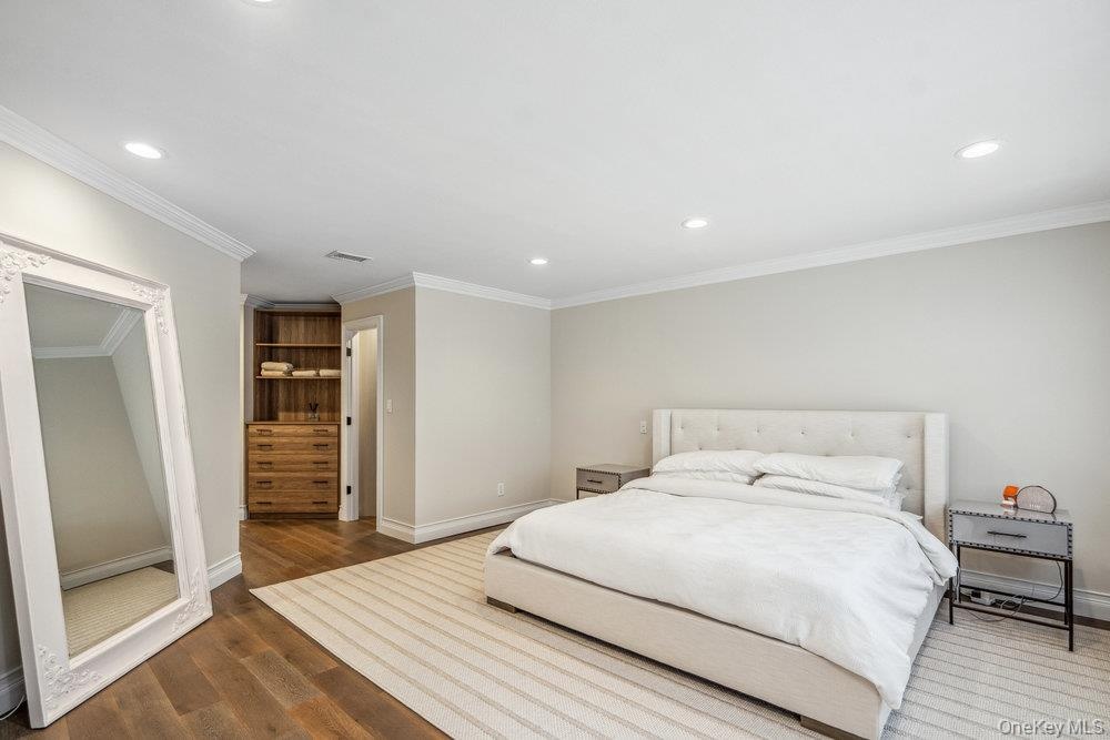 Recessed lighting, crown molding, wood-finish flooring, built-in shelving, and a built-in dresser