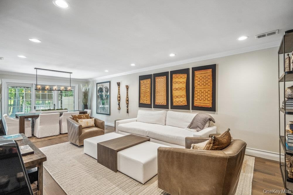 Open-concept living space with recessed lighting, crown molding, and wood-finish flooring