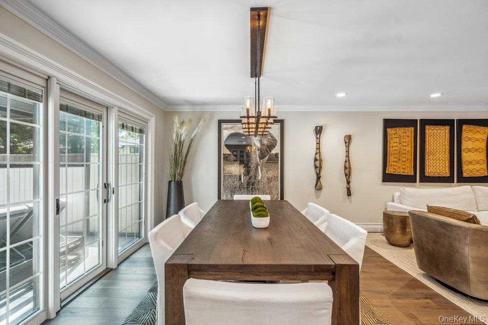 Dark wood finish dining table with a linear chandelier, recessed lighting, and crown molding