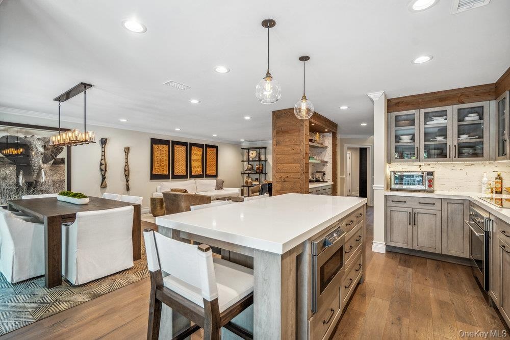 Open-concept kitchen and dining area featuring wood-finish flooring, recessed lighting, and a kitchen island with built-in appliances