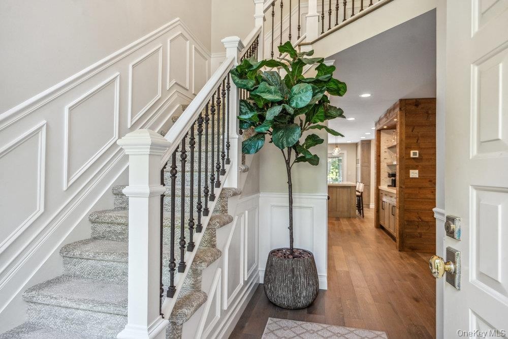 Hardwood flooring, wainscoting, wrought iron balusters, panel-style interior door, and built-in cabinetry