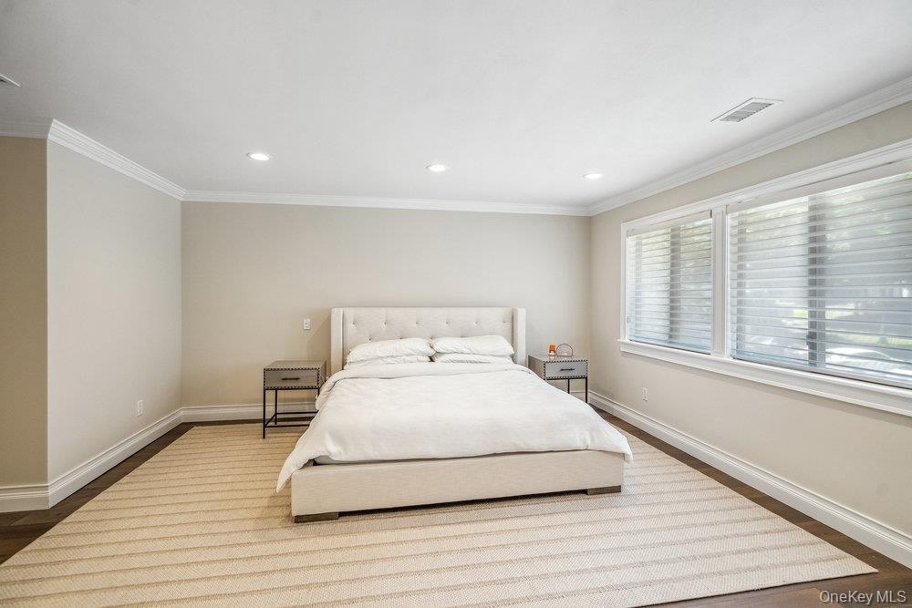 Recessed ceiling lighting, crown molding, wide plank wood-finish flooring, and large windows with blinds