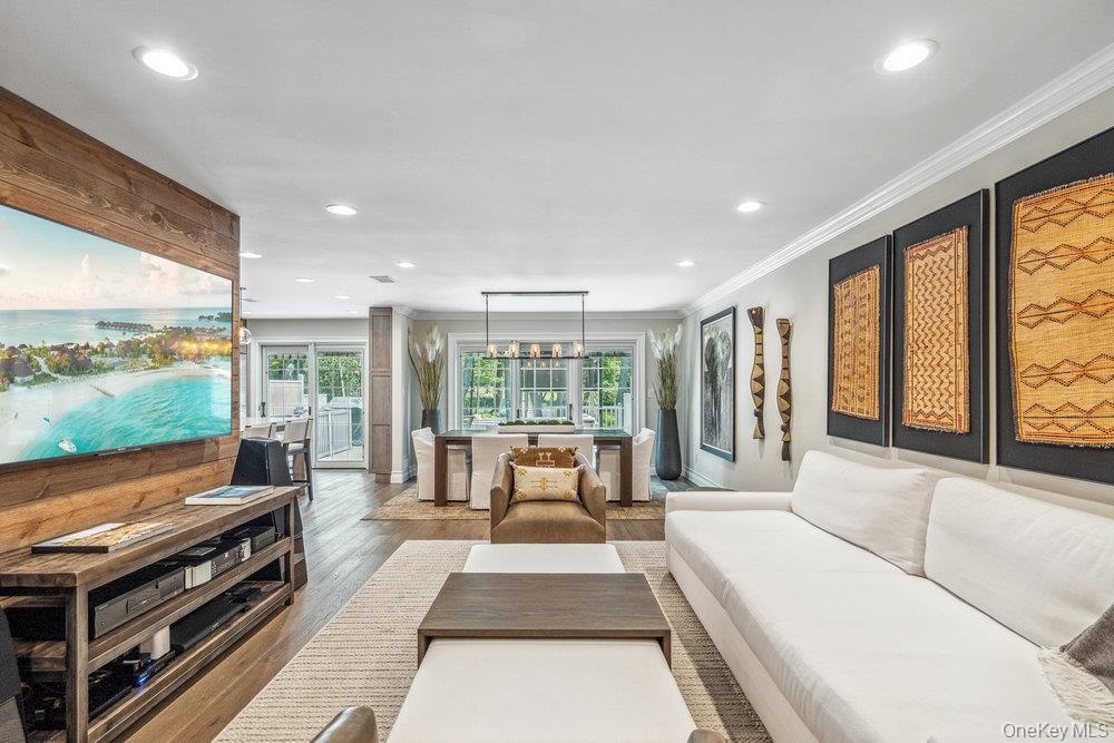 Open-concept living area with wood-finish flooring, recessed lighting, and crown molding