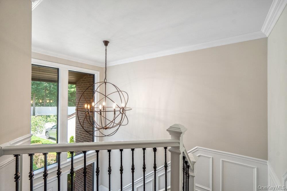 Spherical chandelier, crown molding, wainscoting, tall window, wrought iron balusters