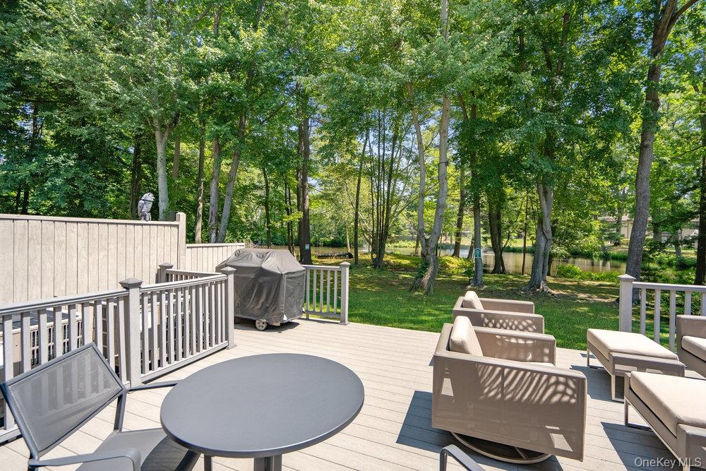 Expansive outdoor deck featuring wood-finish flooring, protective railing, and a private wooded backdrop
