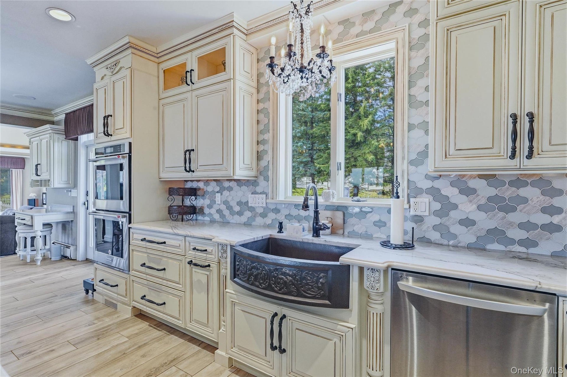 White cabinetry with dark hardware, a decorative marble backsplash, stainless steel appliances, a black farmhouse-style sink, quartzite counter tops