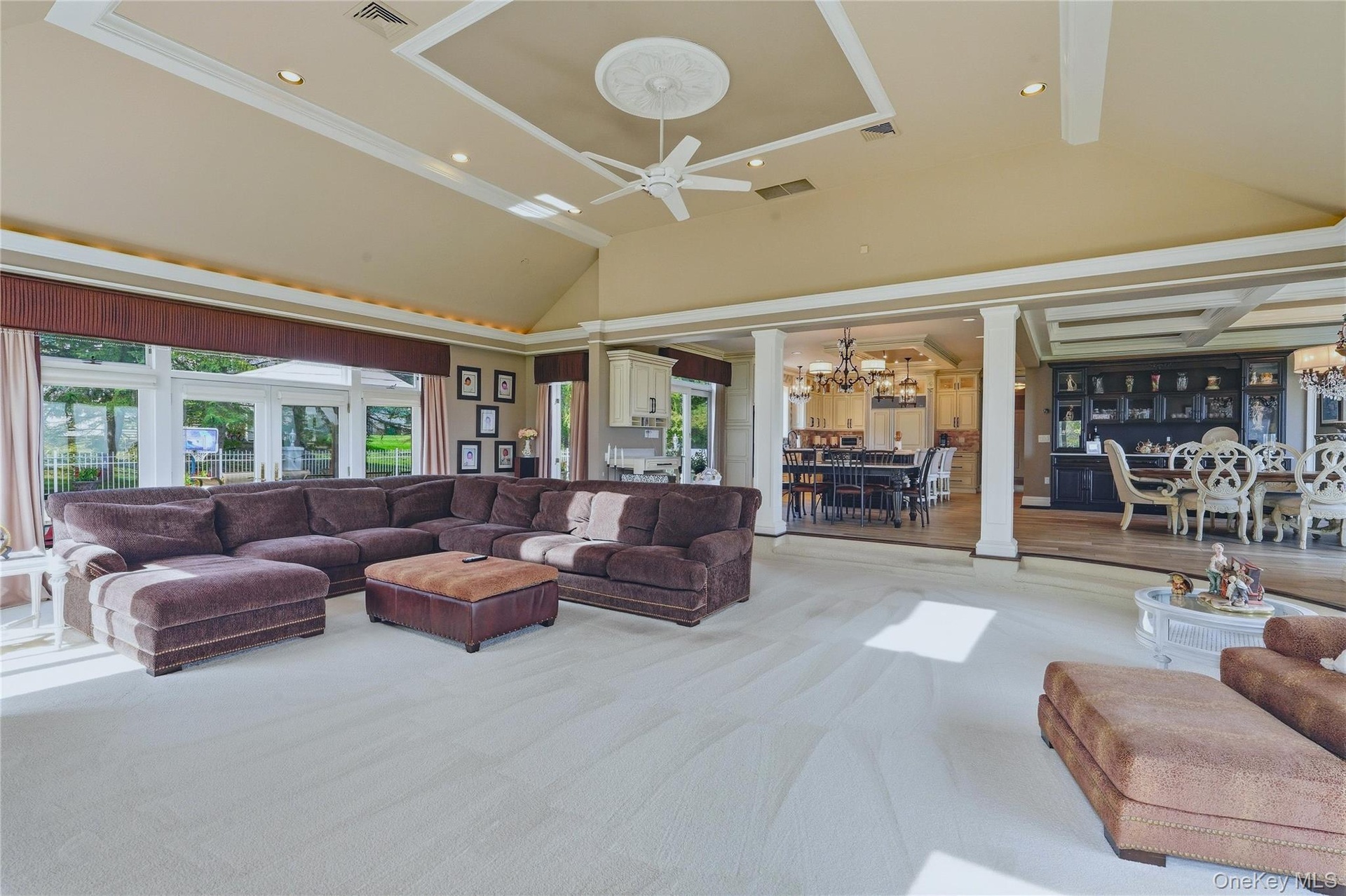 Vaulted ceiling with recessed lighting, large windows, tray ceiling with medallion, ceiling fan, and built-in cabinetry
