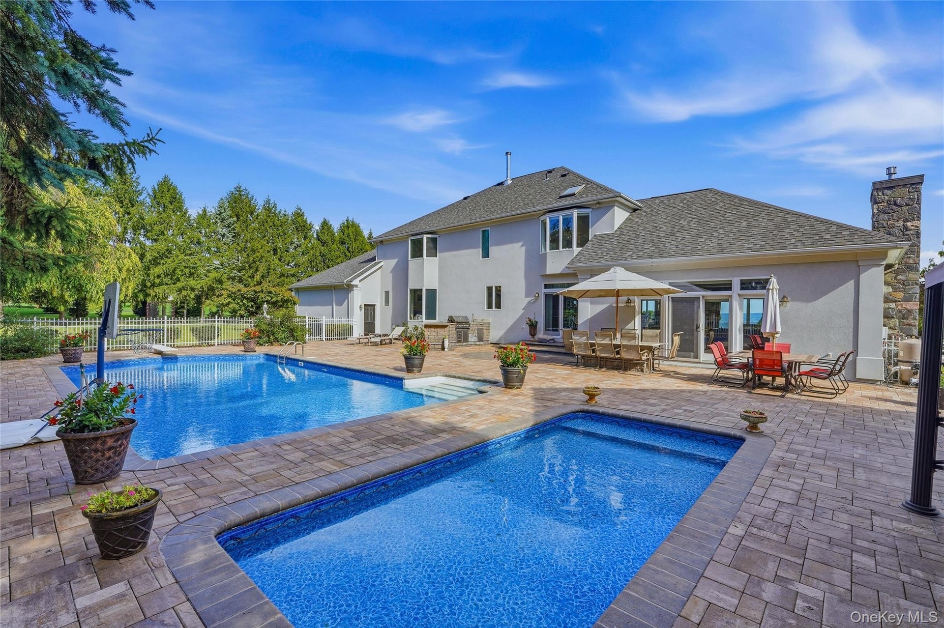 Expansive paver patio with a rectangular pool and an additional plunge pool