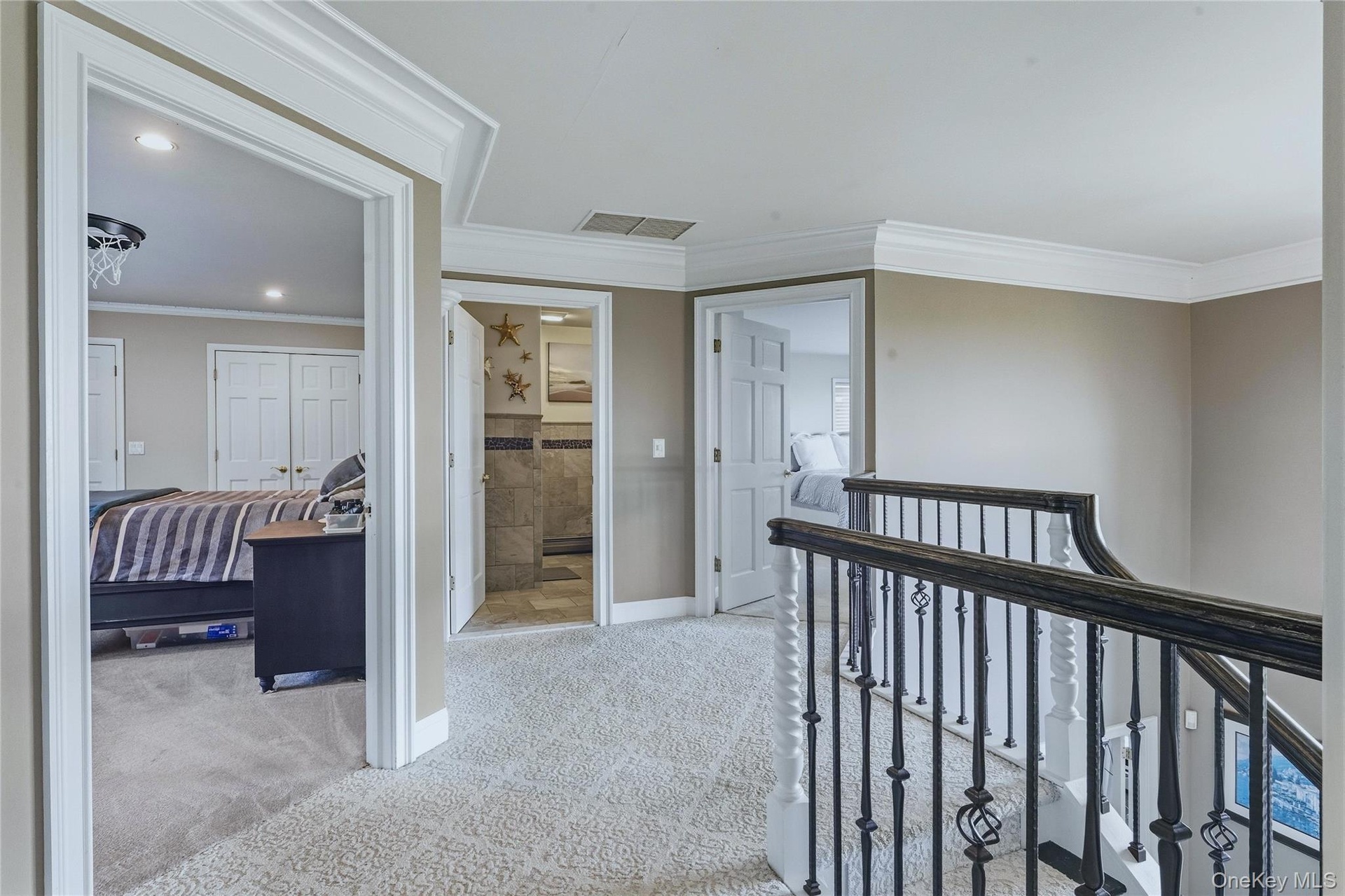 Upper-level hallway with carpeted flooring, crown molding, recessed lighting, and a wrought iron banister