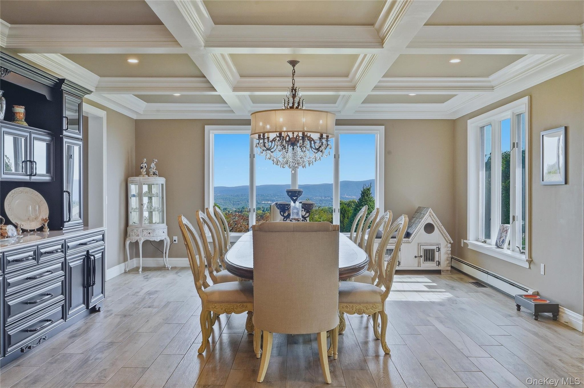 Coffered ceiling with recessed lighting, built-in cabinetry, large windows, mountain views and a chandelier