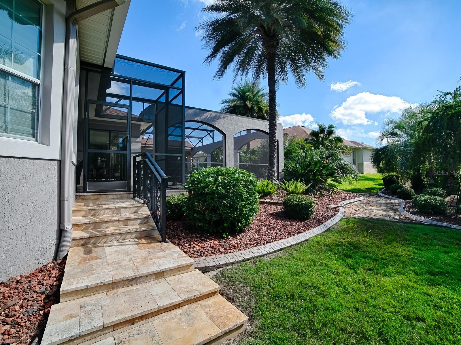 THIS IS THE RIGHT SIDE OF THE HOME WITH TRAVERTINE STEPS LEADING TO THE POOL AREA.