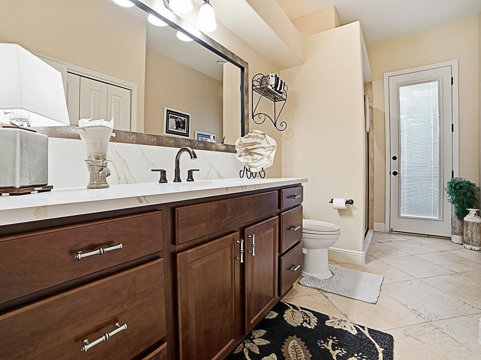 ACROSS THE HALLWAY FROM THE 3RD BEDROOM IS THE 3RD "POOL" BATH OFFERING ACCESS FROM THE INSIDE AND OUTSIDE.  THERE IS A SHOWER TO THE LEFT AND LARGE L