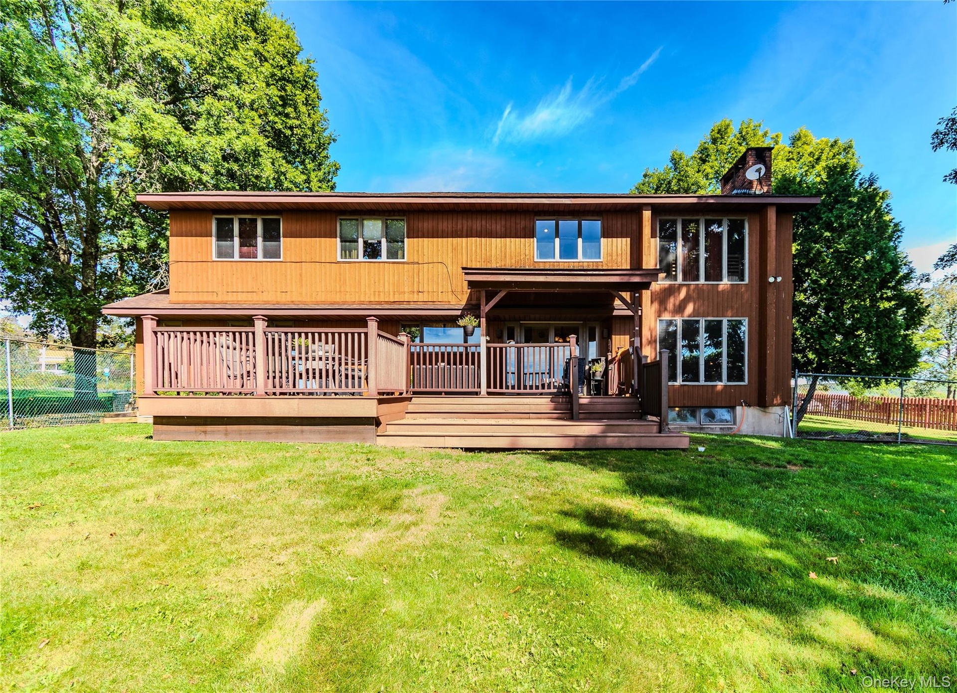 Expansive backyard with a manicured lawn, a multi-level wood deck, and a wood-sided exterior