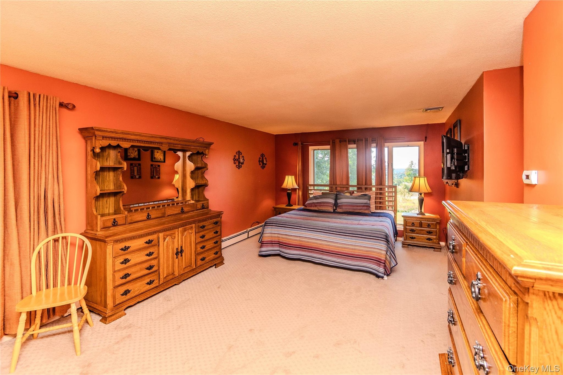 Expansive room with carpeted flooring, multiple windows, and a wall-mounted television bracket
