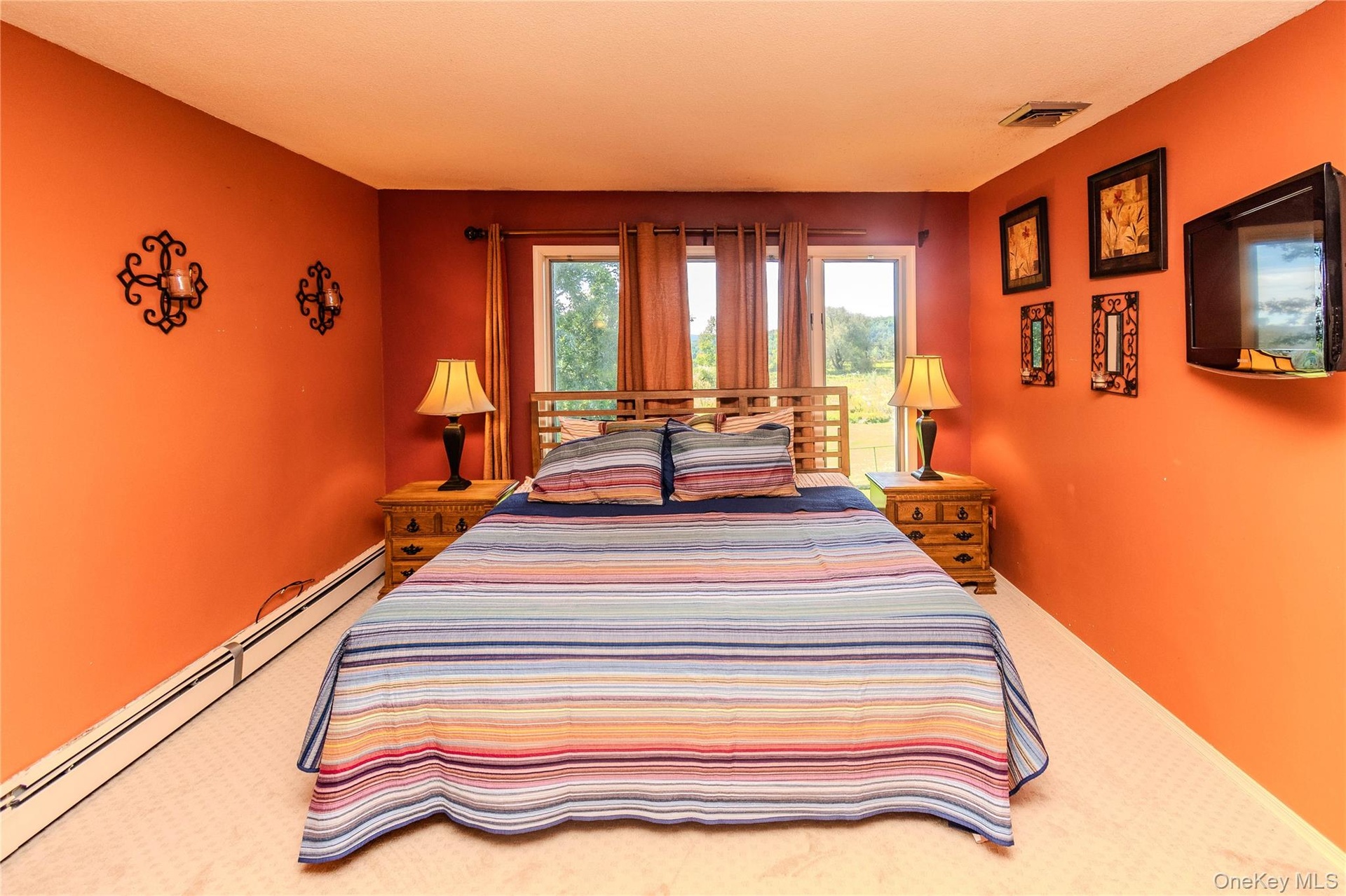 Carpeted room featuring multiple windows, baseboard heating, and warm-toned walls