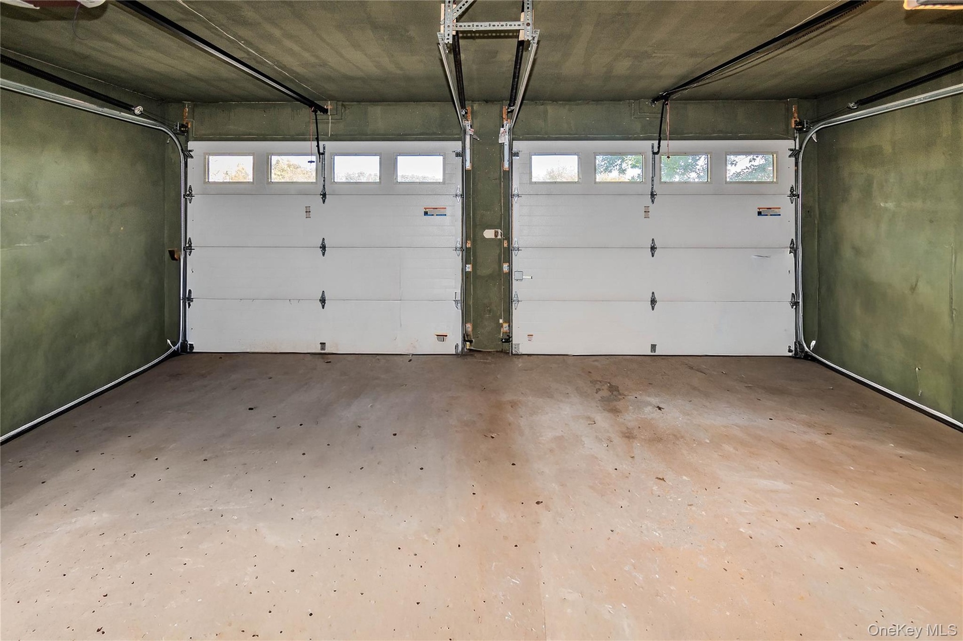 Two-car garage featuring concrete flooring and two white overhead doors with individual window panels