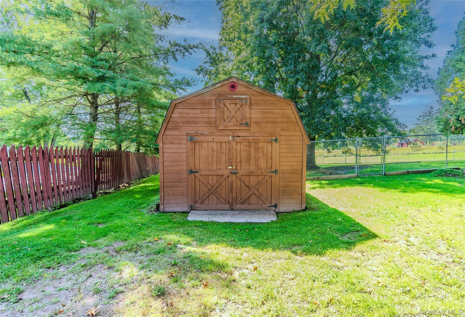 Barn-style shed with double doors, wood siding, and an overhead window