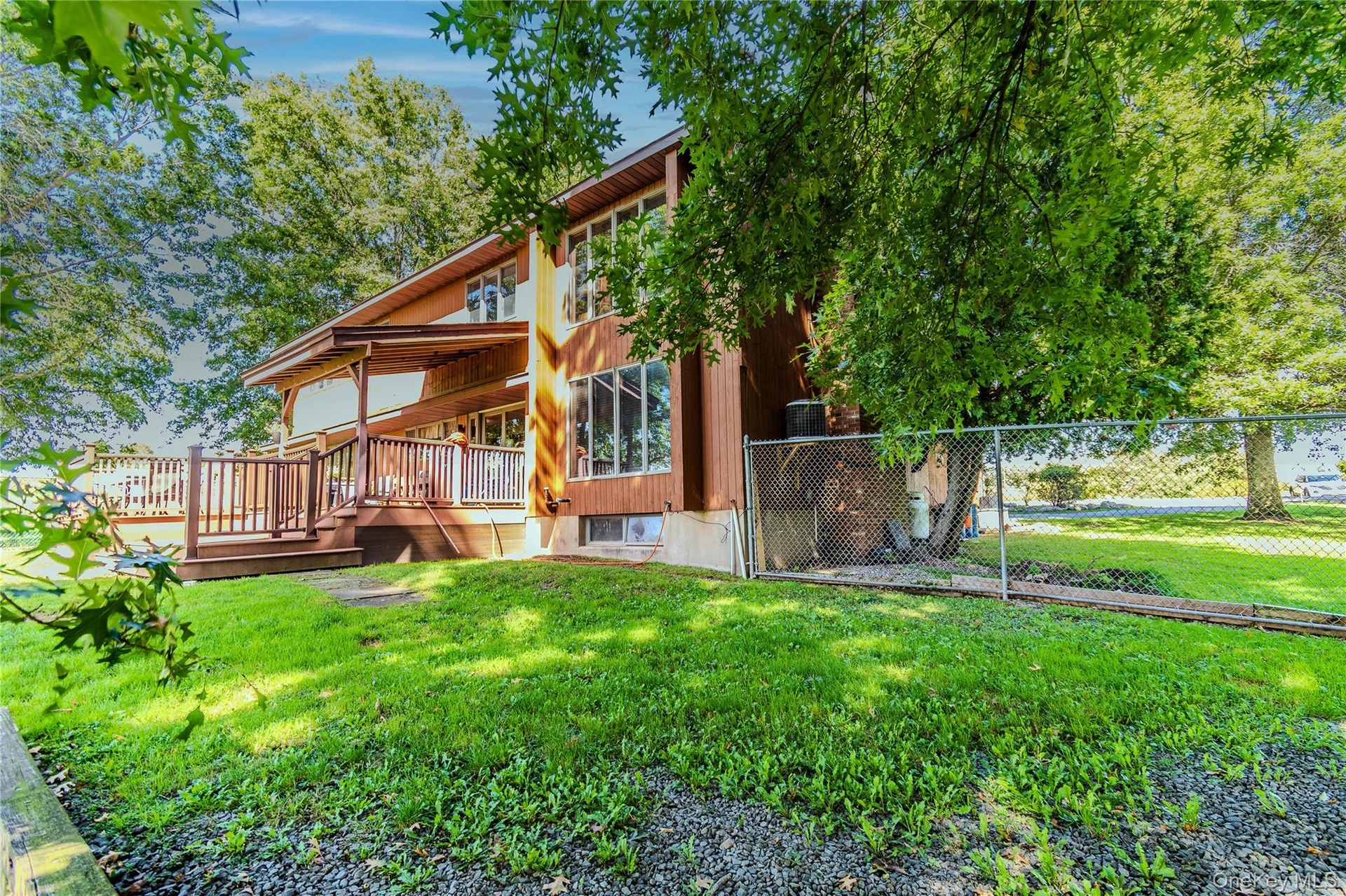 Multi-level exterior with wood siding, expansive wood deck, and abundant windows