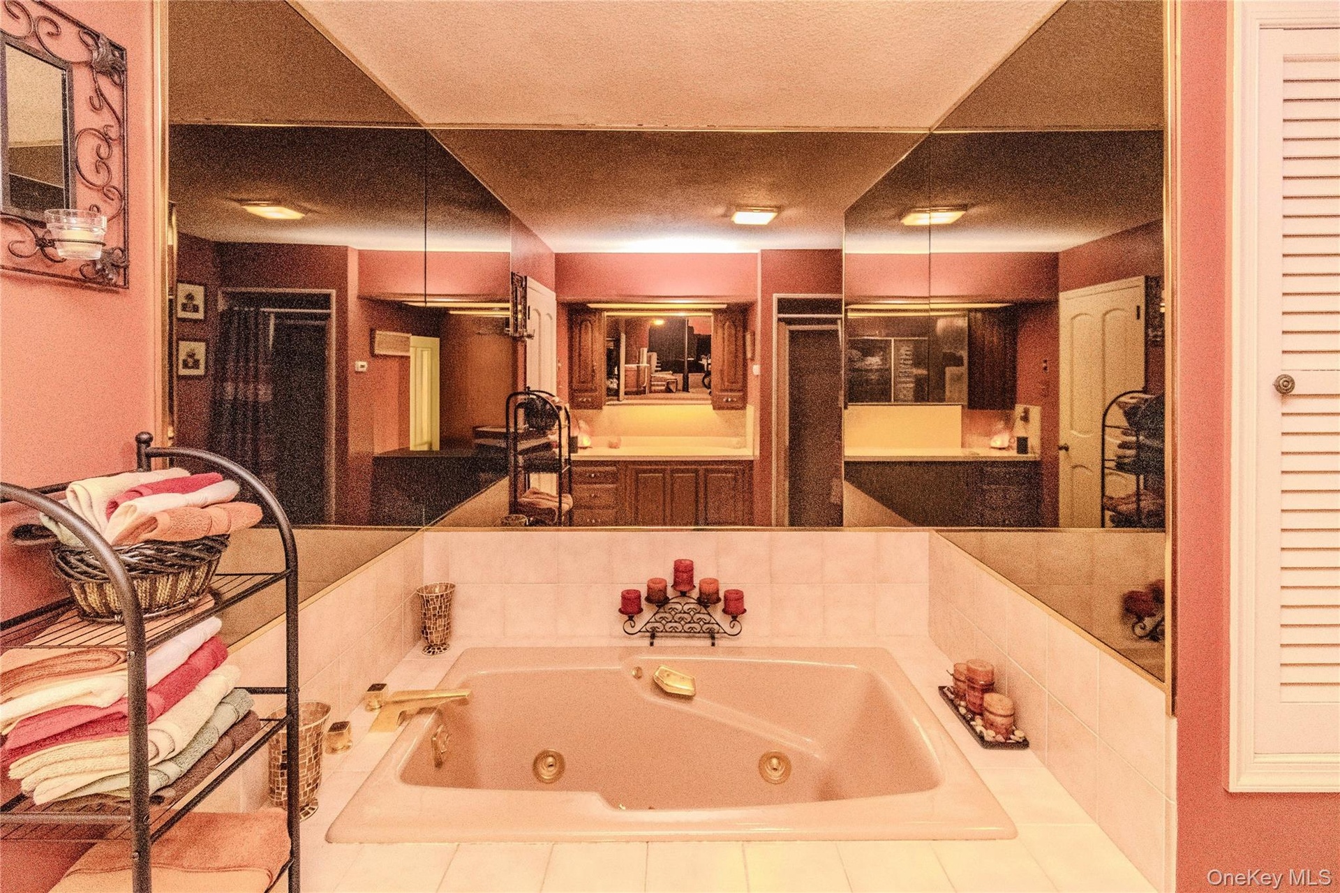 Jetted tub with gold-tone fixtures, surrounded by white tiled decking