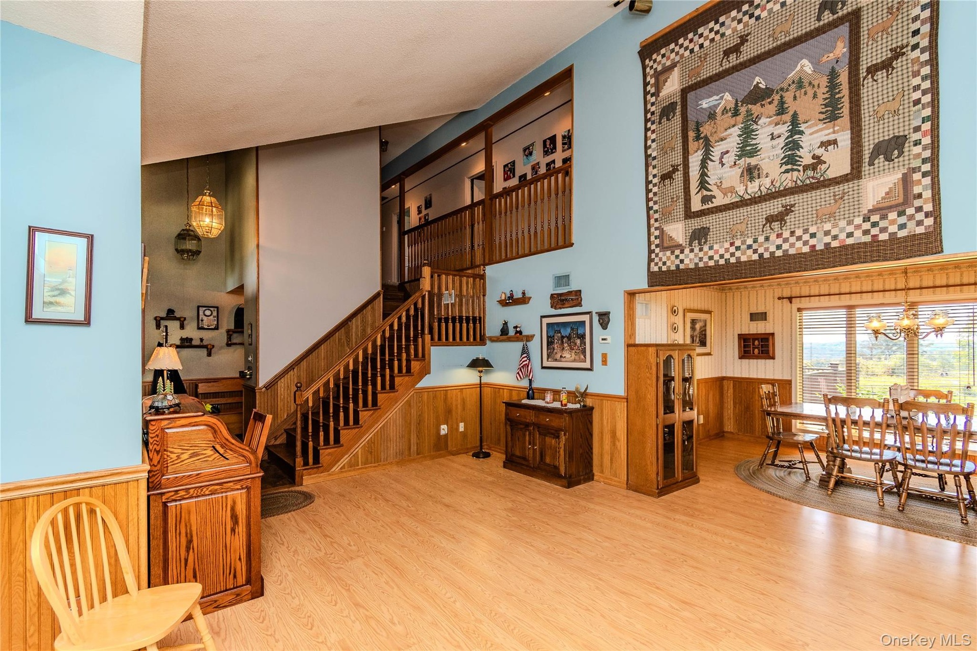 Vaulted ceiling, wood-finish flooring, wood paneling, open-concept design, and a multi-level staircase with wood railing
