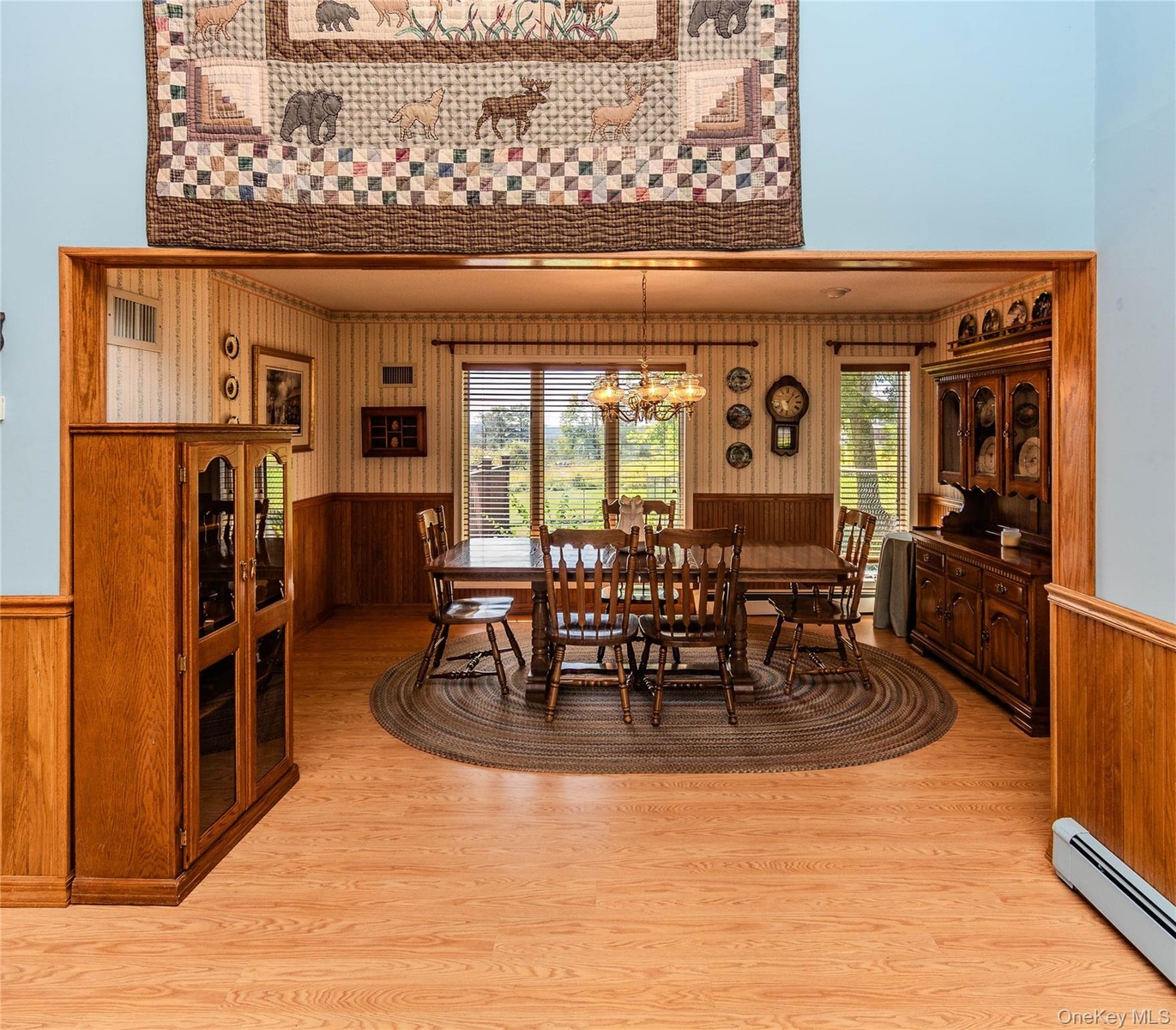 Wood-finish flooring throughout, with a dining area featuring wood wall paneling and a chandelier
